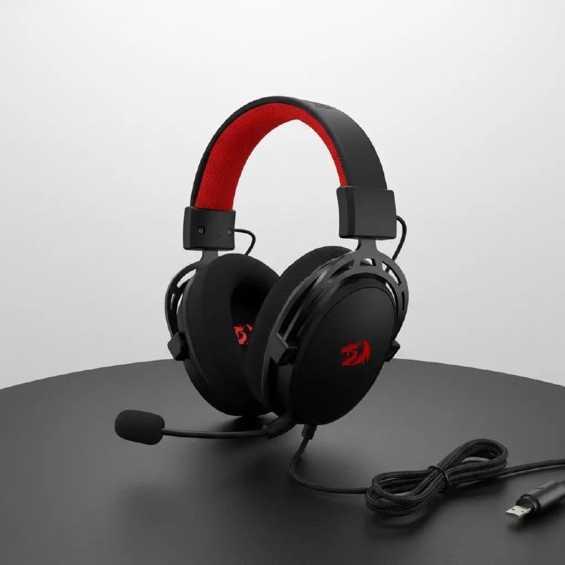 Headset gamer Redragon Cragblade H541 na cor preta com detalhes em vermelho no arco, microfone acoplado e cabo USB, posicionado sobre uma mesa preta.